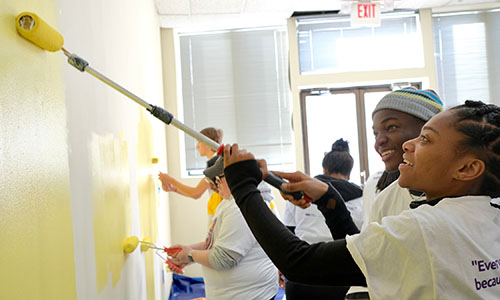students painting a wall yellow