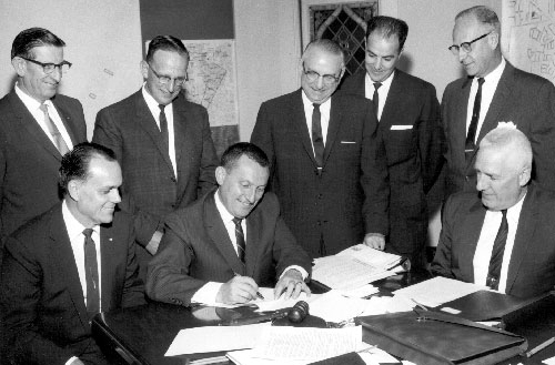Photo of officals signing document during the 1950s