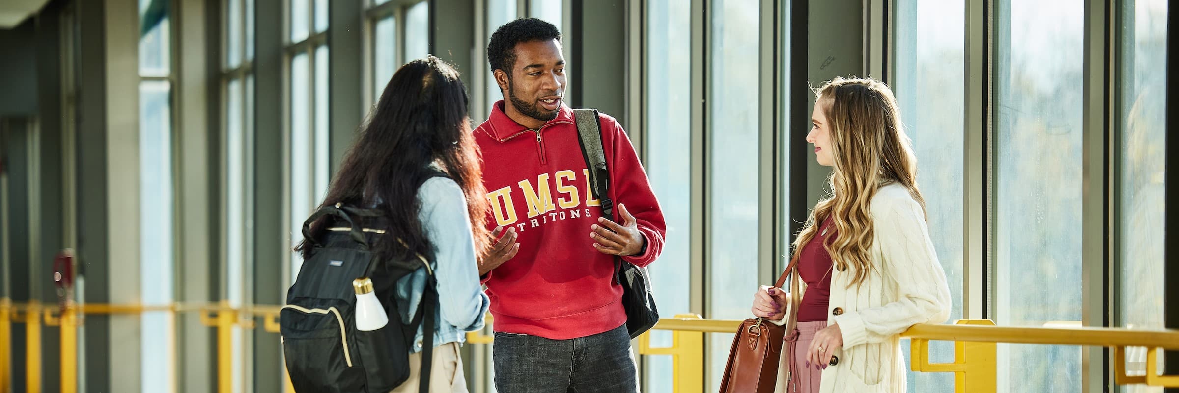 Three students chat in the Bridge on UMSL's North Campus