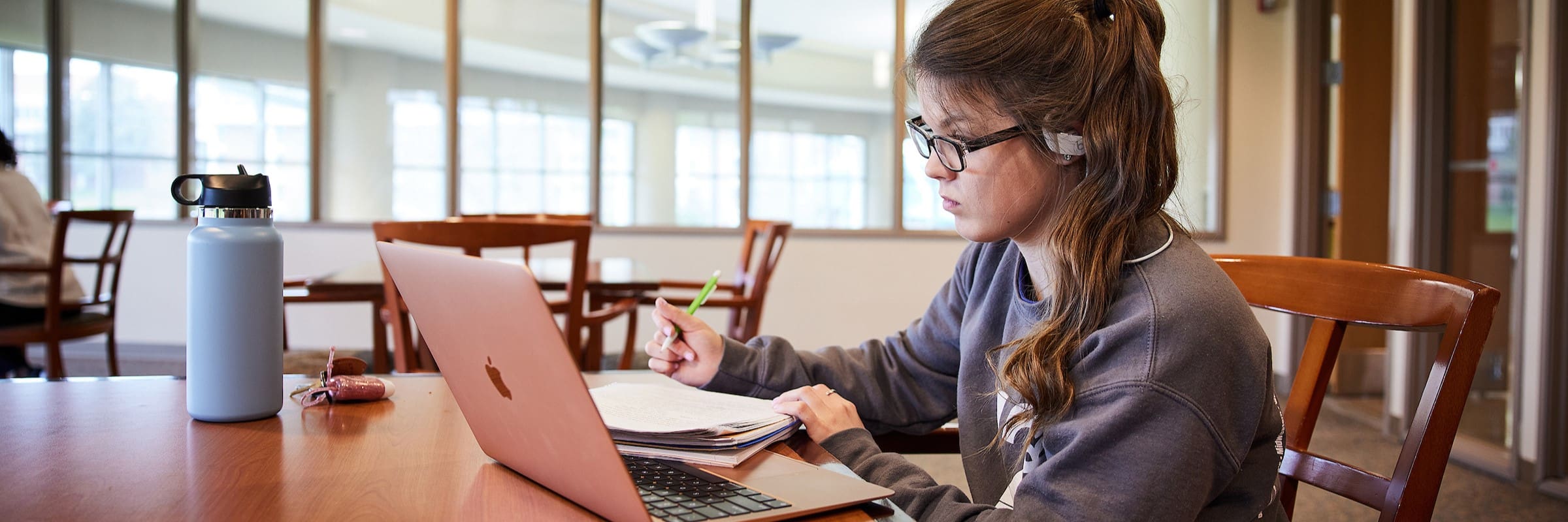 A student takes notes from their laptop in a study room