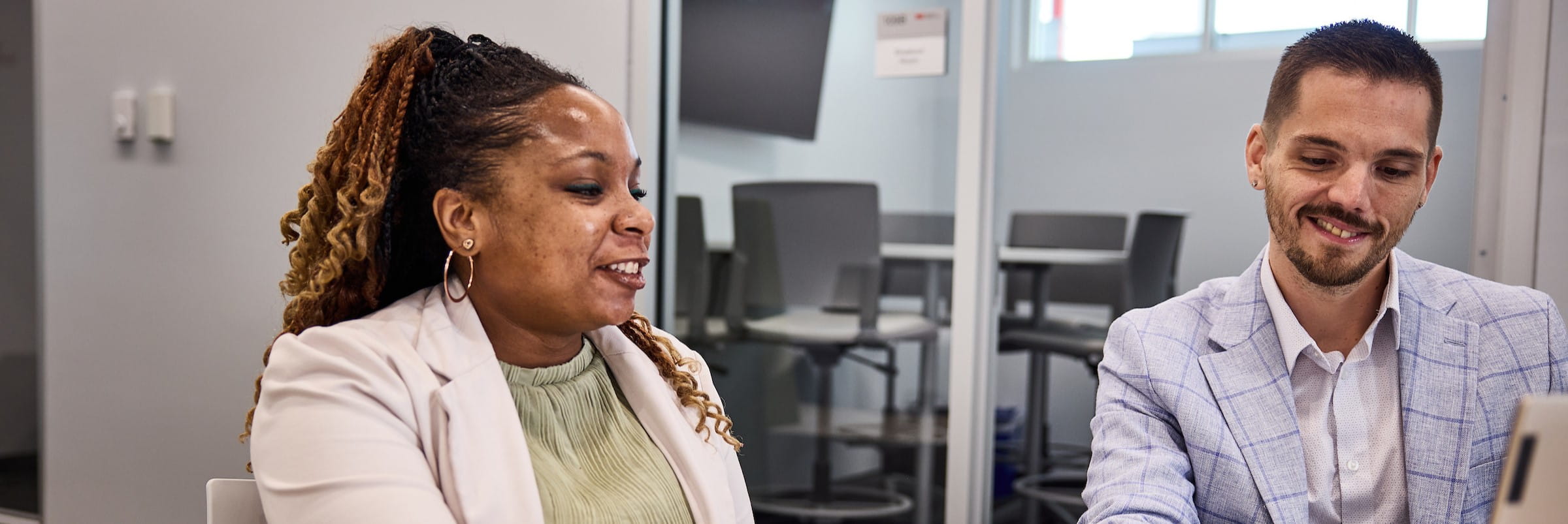 Two staff members talk in an office setting
