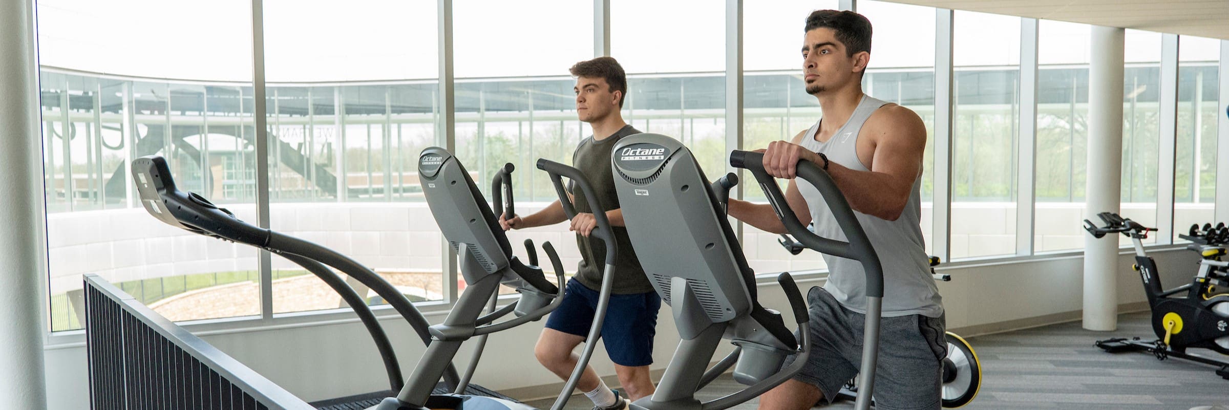 Two students use equipment in the Recreation and Wellness Center