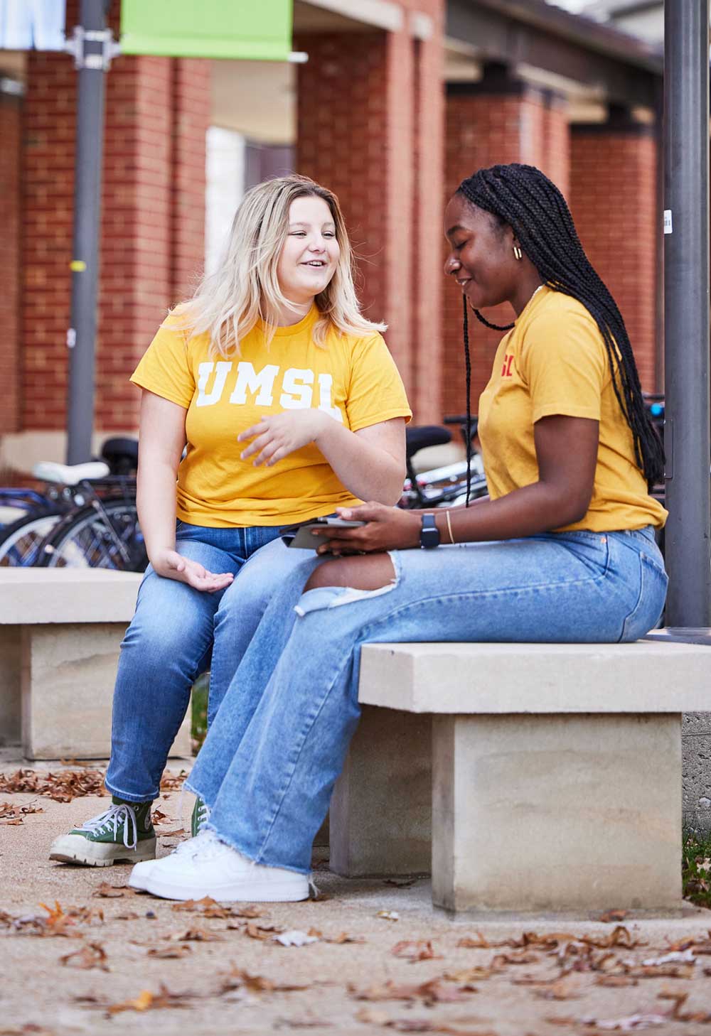 Two students outside on a bench in conversation