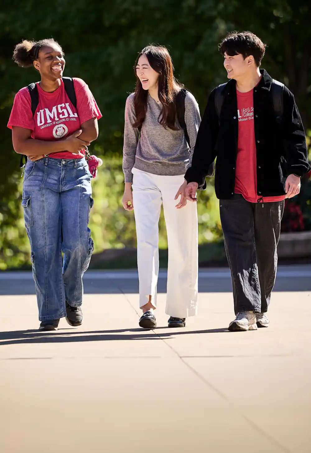 Three students walking down a sidewalkm