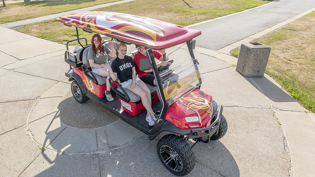 Photo of tour guide and guests on a golf cart on campus.