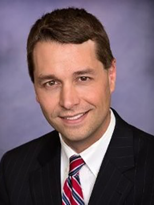 Headshot of Joe Blanner in front of a blue backdrop.