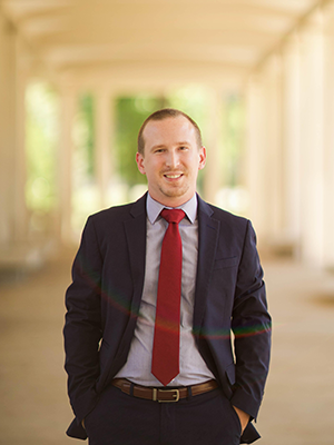 Board member Samuel Fredeking stands on a patio wearing a suit and tie.