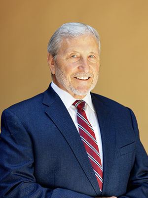 Studio portrait of Stan Anderson in front of a gold backdrop.