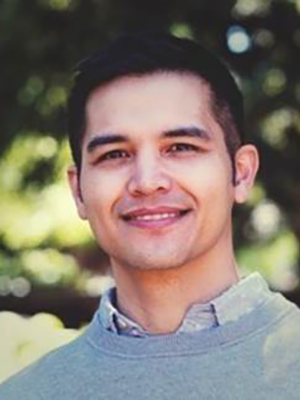Headshot of Tim Wombles standing outdoors in front of greenery.