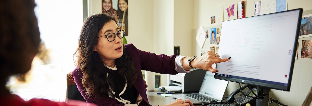 Academic Advisor talking with a student while pointing at a computer screen
