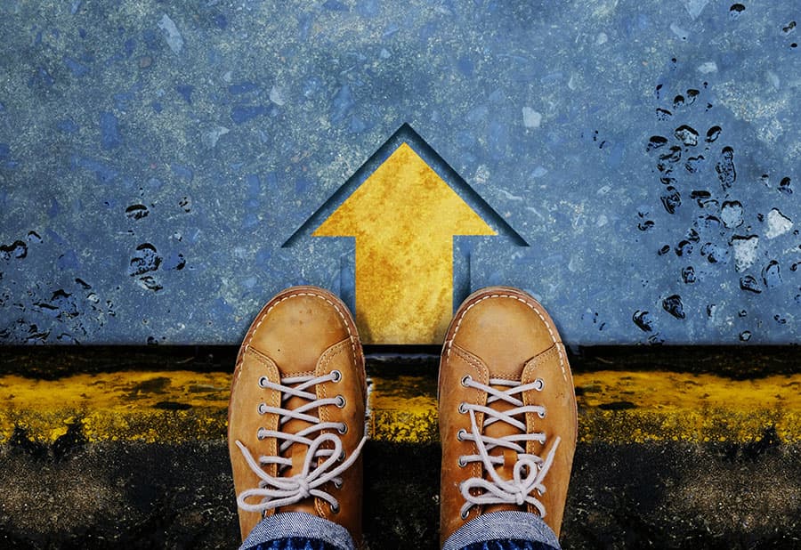 A pair of brown shoes standing on a wet surface with a yellow upward arrow and a yellow line indicating a boundary.