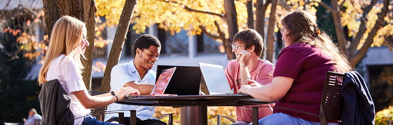 Students sitting at a table outside studying.