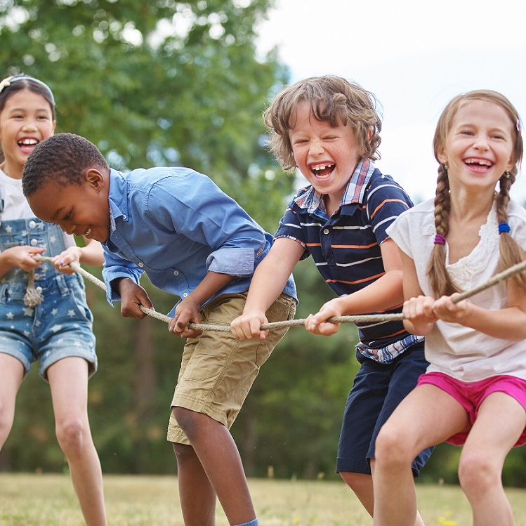 Children joyfully participating in a tug-of-war game outdoors.