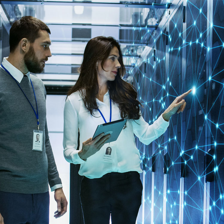 Two professionals examining digital network connections in a server room, highlighting technology and teamwork.