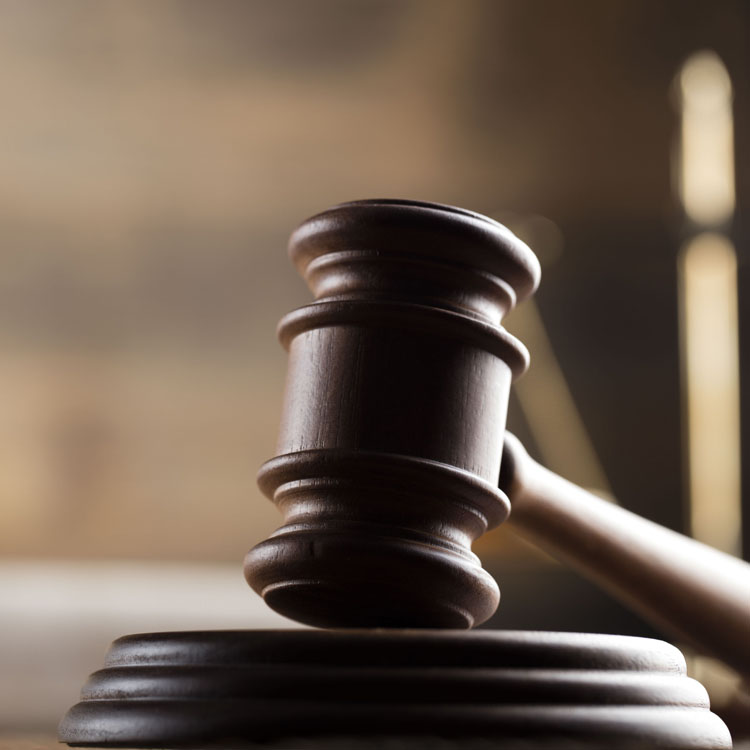 A wooden gavel resting on a sound block, symbolizing justice and authority in a courtroom setting.