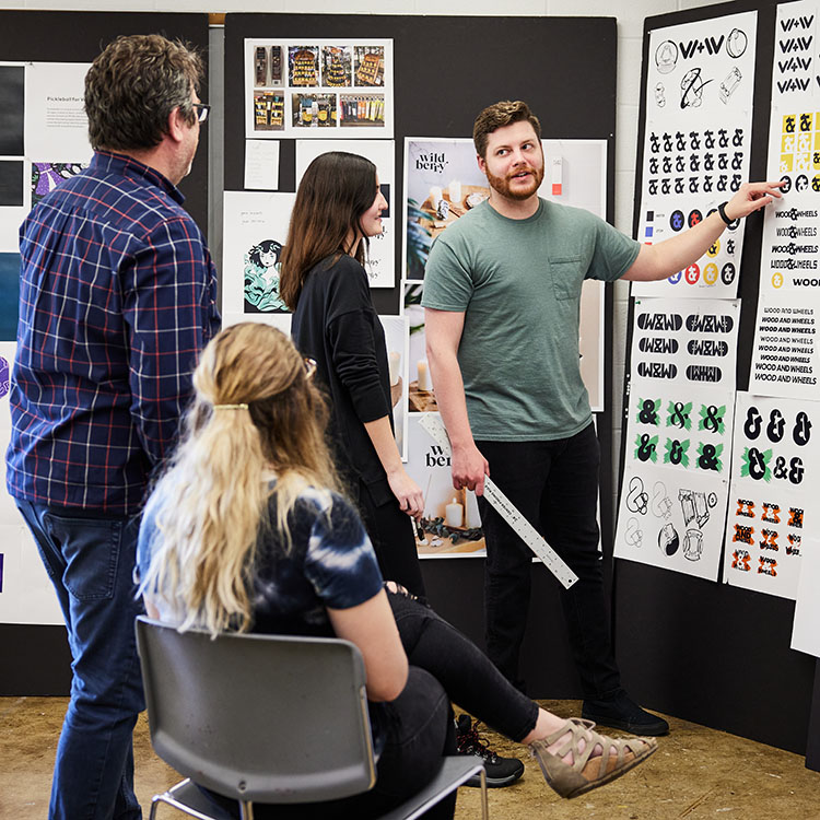 A designer presents concepts to a small group during a collaborative brainstorming session in a creative workspace.