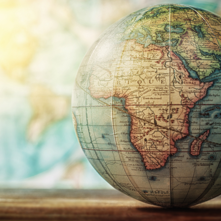Vintage globe highlighting the continent of Africa, set against a blurred world map background.
