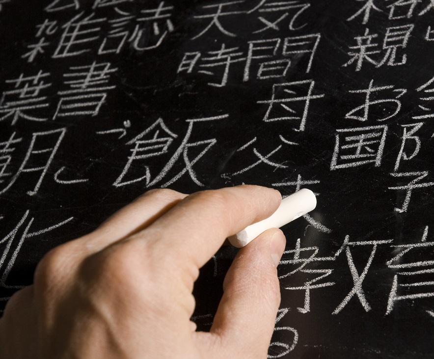 Person writing in Japanese language on chalkboard