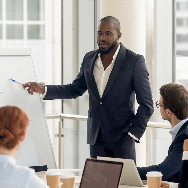 A businessman in a suit presenting a graph to a group during a meeting in a modern office setting.