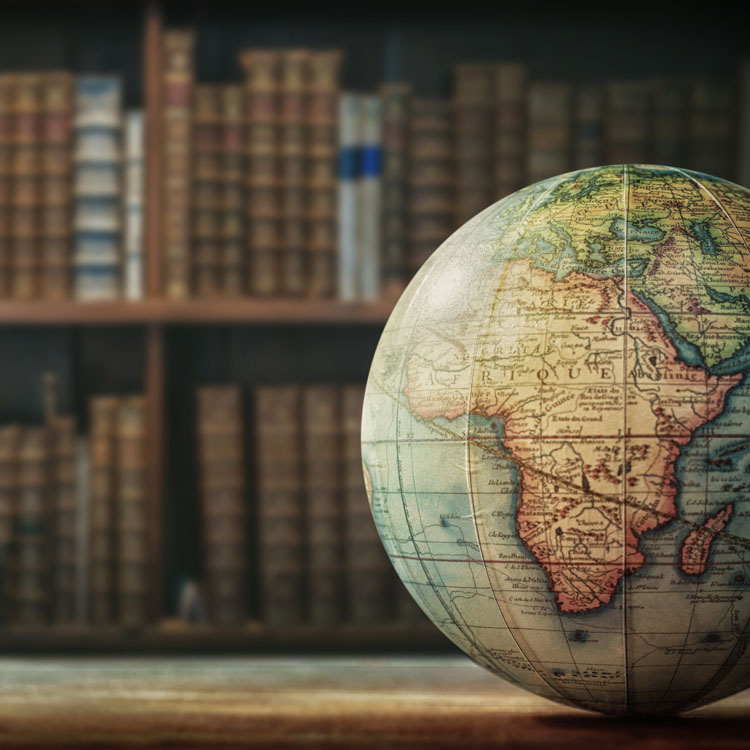 A vintage-style globe highlighting Africa, set in front of a bookshelf filled with old books.