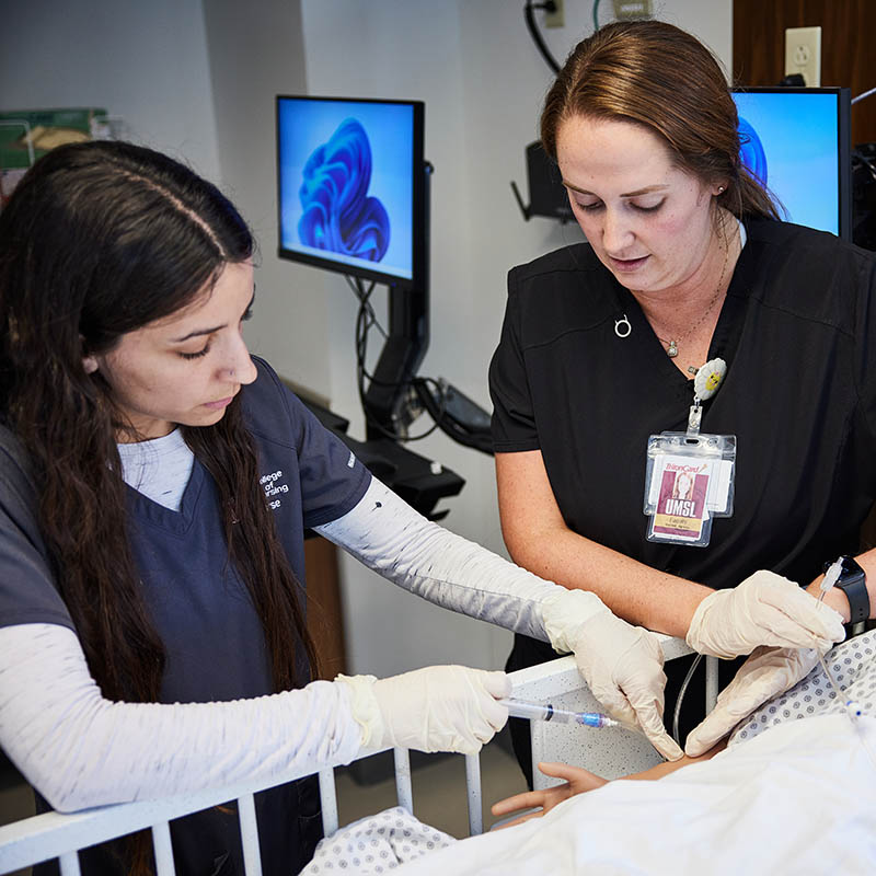 Nursing professionals demonstrate intravenous insertion techniques on a patient in a clinical training environment.