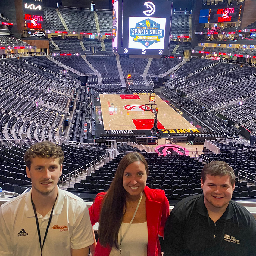 2 students and 1 professor in front of empty basketball staidum