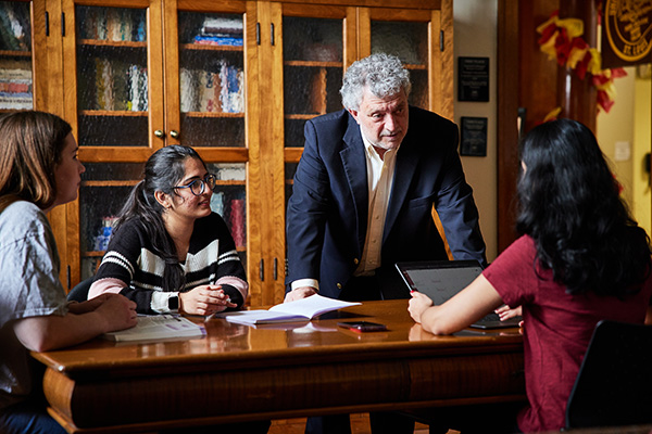 3 students with a professor in the Honors College