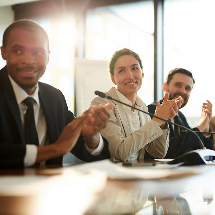A business team applauding during a meeting, showcasing engagement and support.