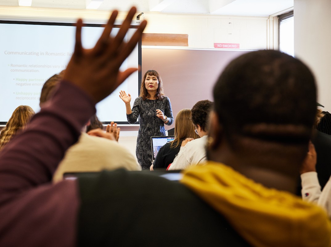 A student raises his hand in front of a professor