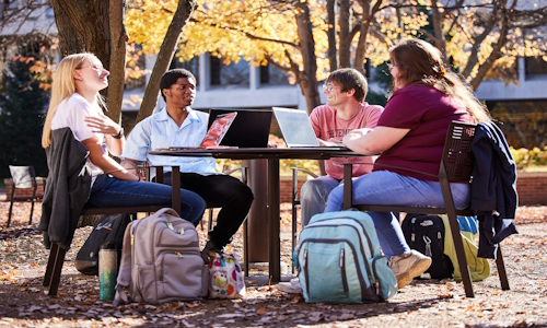 4 students at a table outside