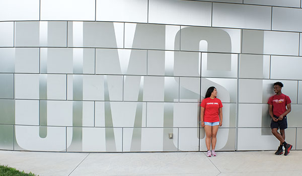 2 students in front of UMSL sign