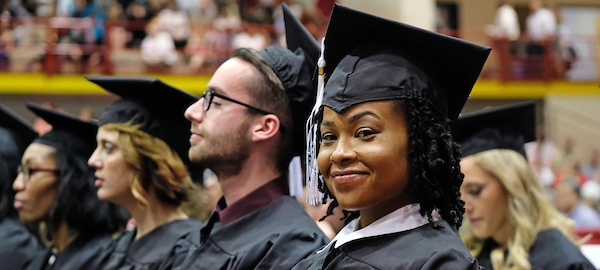 a smiling woman wearing graduation regalia 