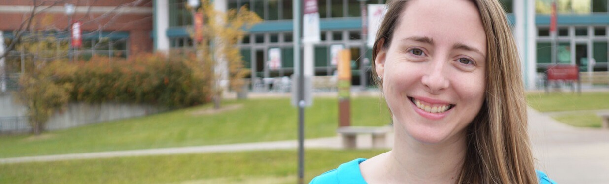 woman smiling with UMSL campus in background