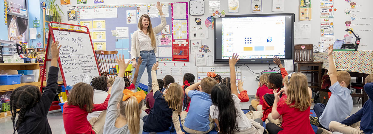 children raising their hands in a classroom