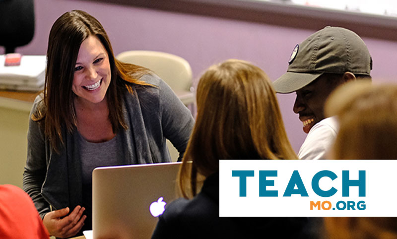 Teacher in classroom with students in from of a laptop