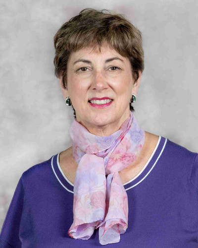 Professional portrait of a woman wearing a light purple scarf and a purple top.