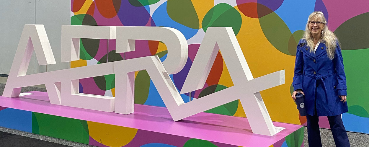 AERA logo displayed in vibrant colors, Dr. Debra Cole in a blue coat standing beside it.