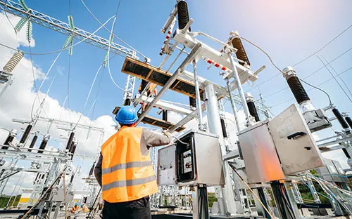 A person measuring mechanical parts with calipers while referencing engineering drawings and specifications