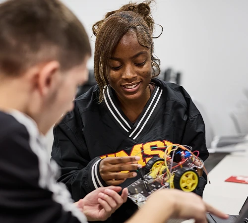 UMSL students collaborating on a robotics project, focusing on assembling components and wiring.