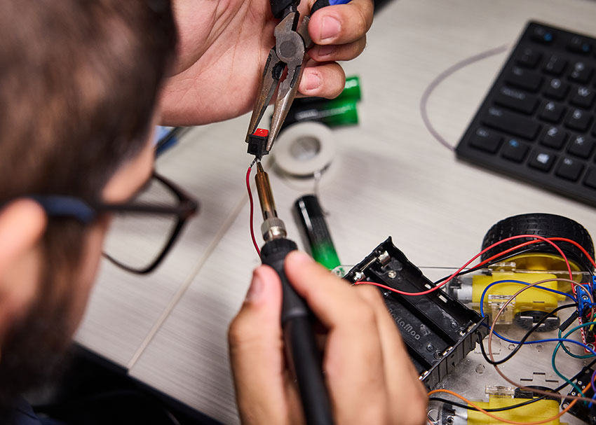 An UMSL engineering student sautering a piece onto a project