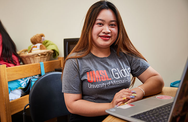 Student in dorm room seated at laptop