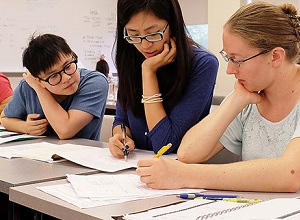 professor looking at a workbook with 2 students