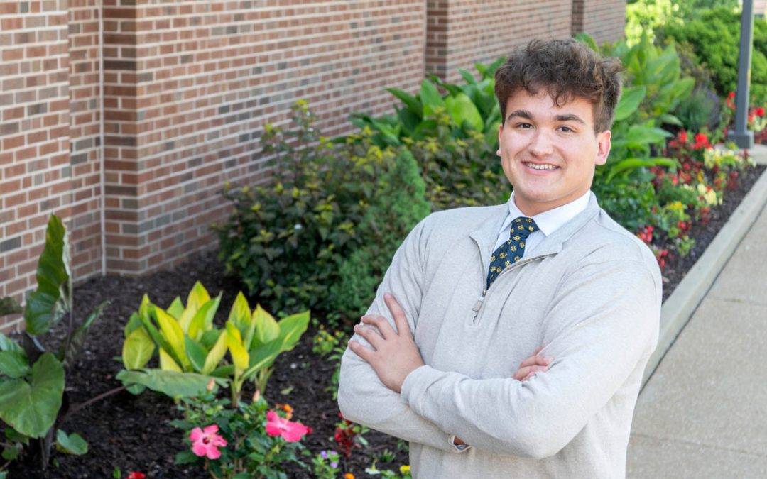 image of a student standing next to a sidewalk with flowers