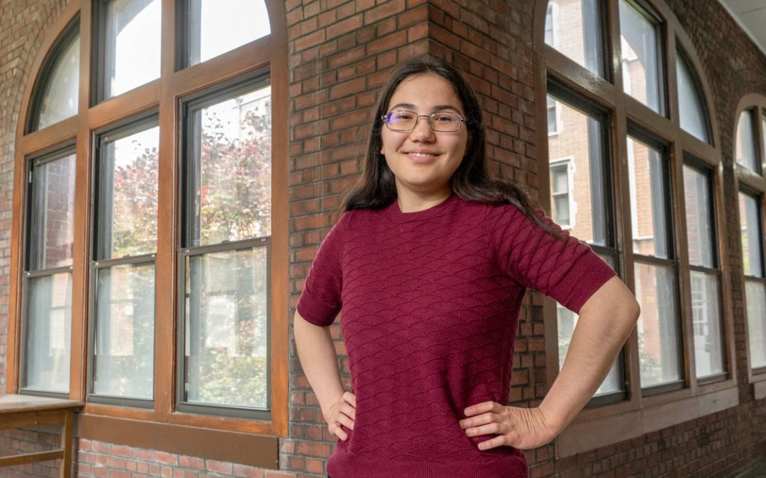photo of a student standing in a hallway with windows
