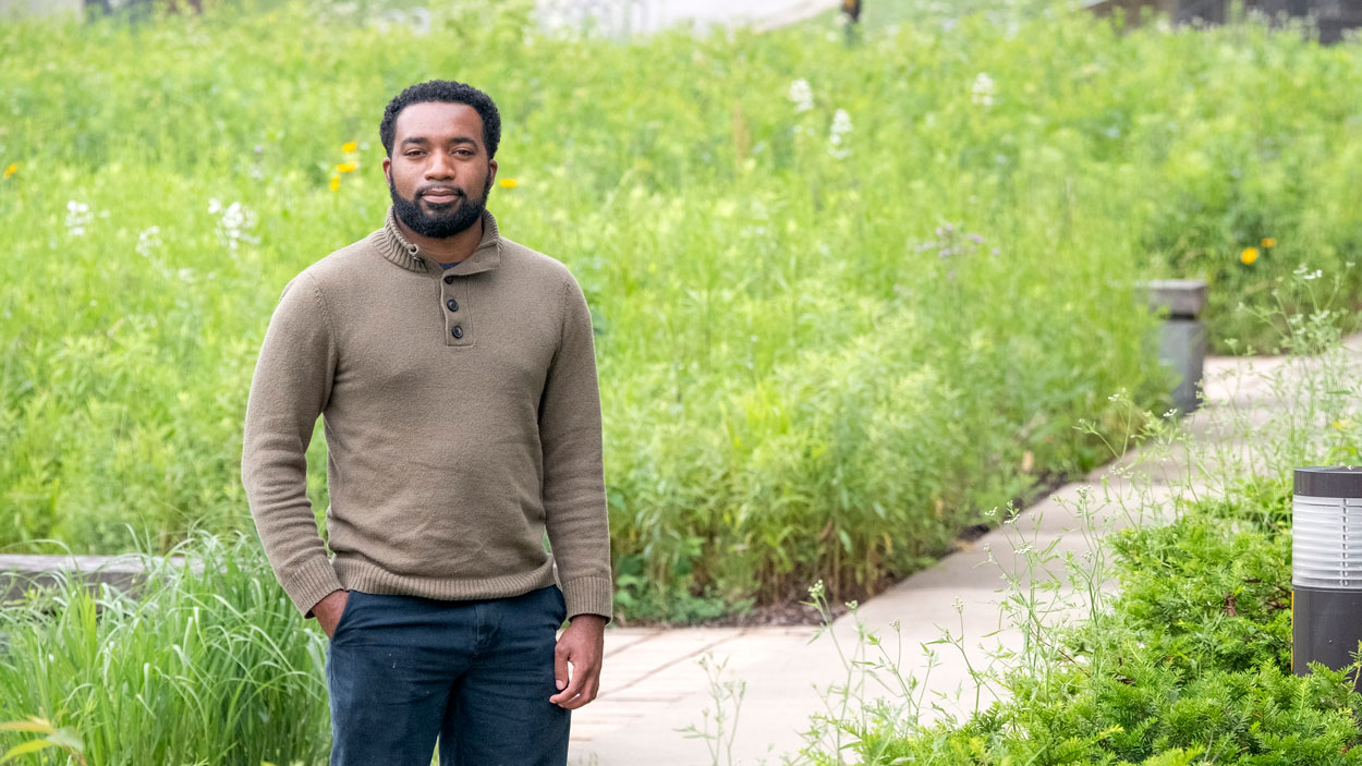 image of a student standing near a walking path and green grass