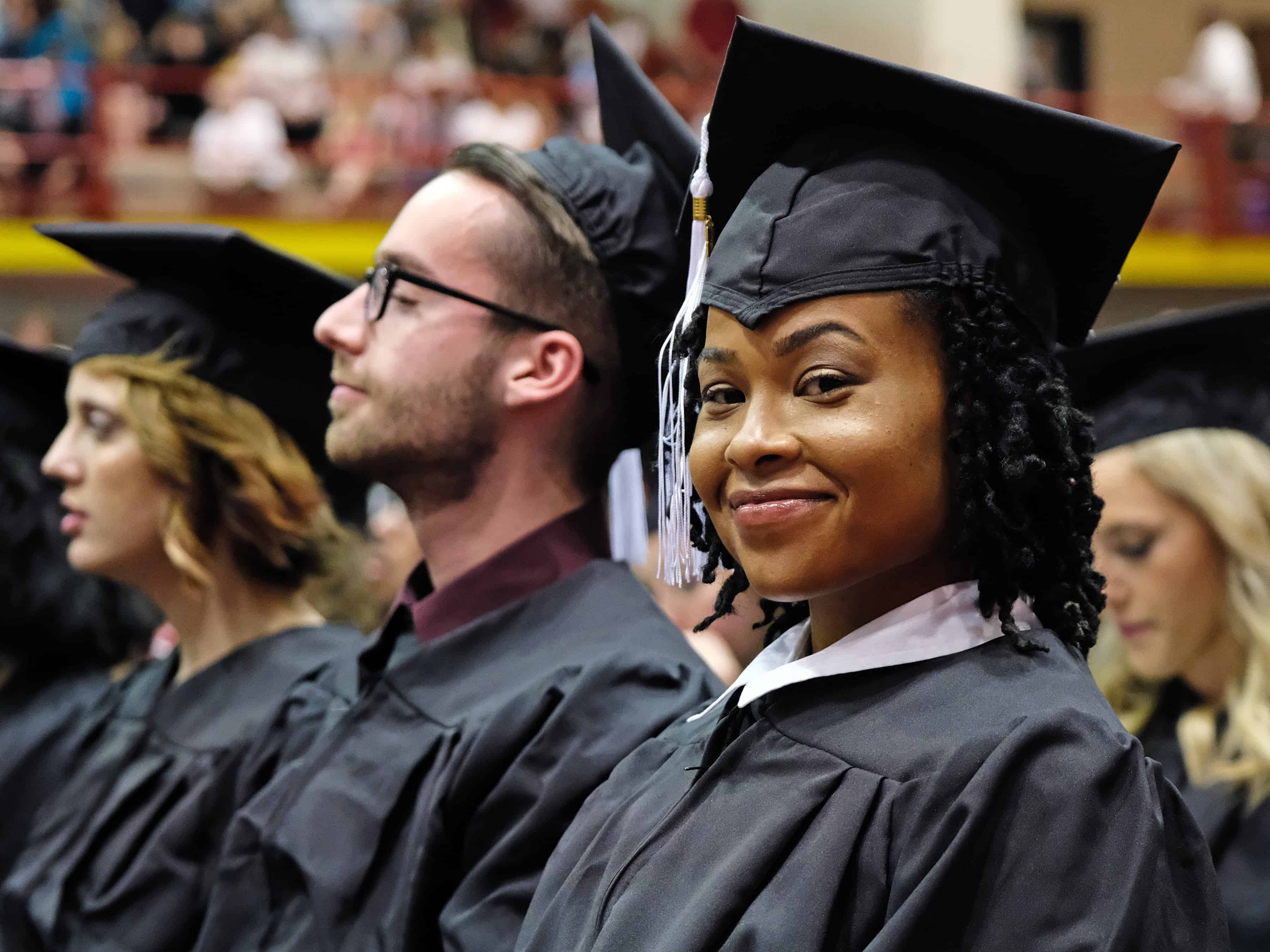 A student smiles for the camera during commencement