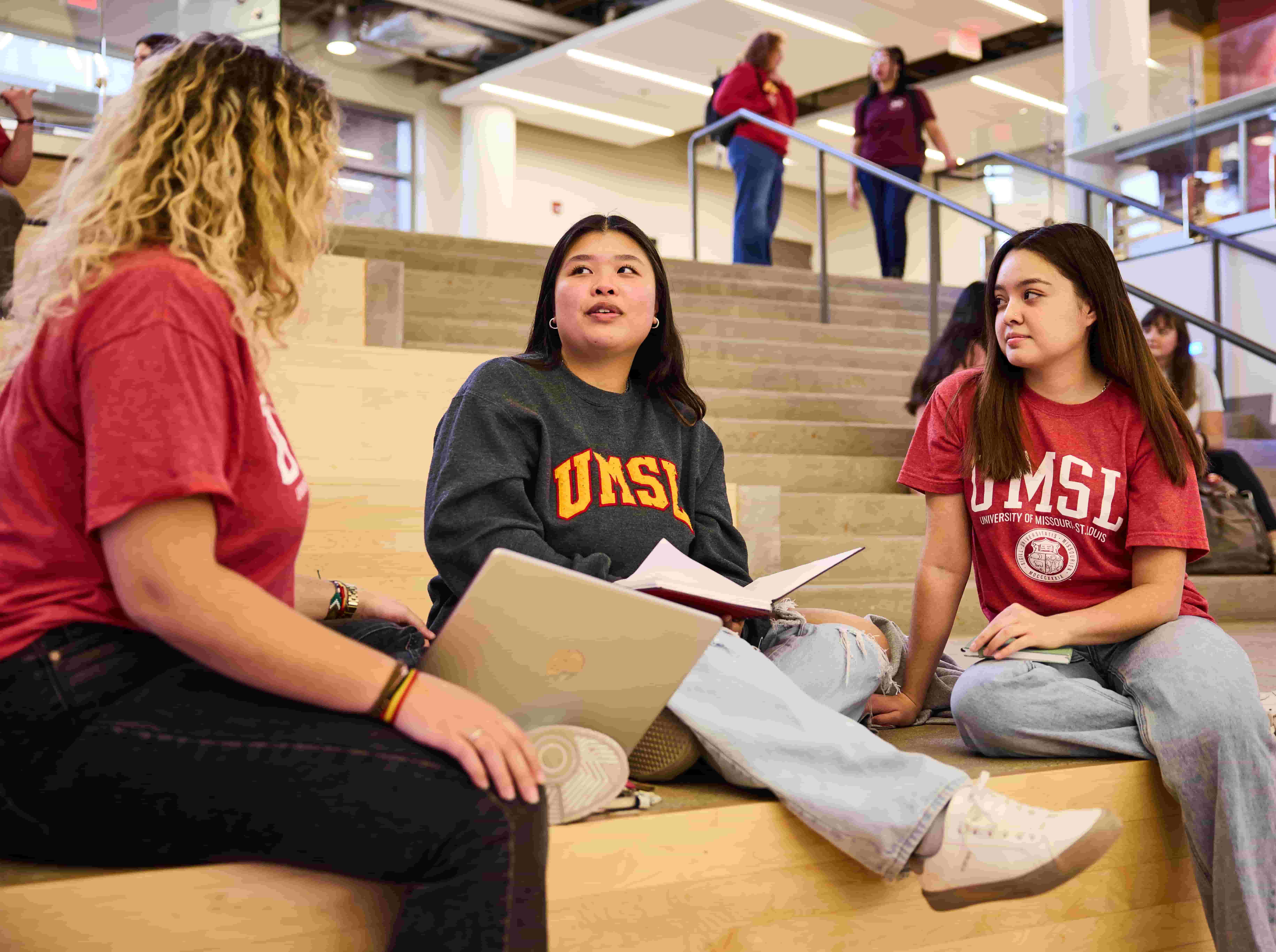 Three students sitting down and chatting in a lobby