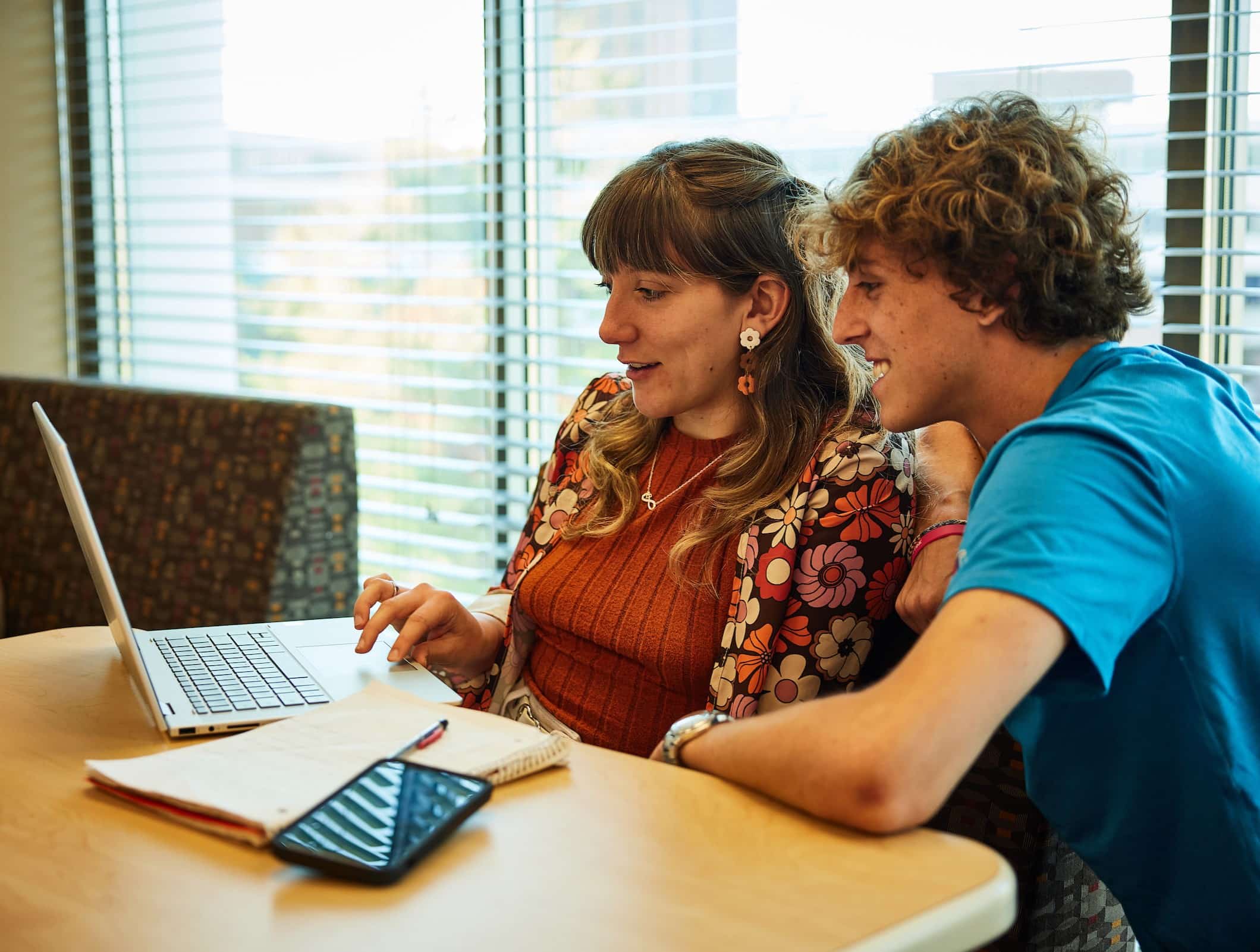 Two students look at a laptop