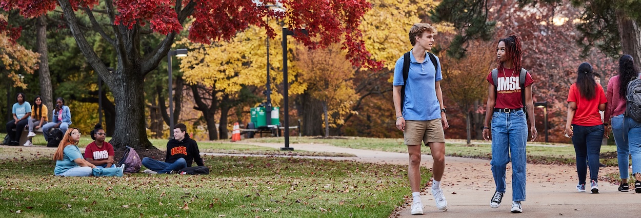 students walking outside under fall trees