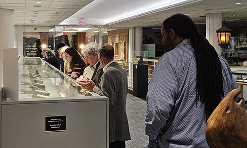 Individuals looking at rare books in a display case.